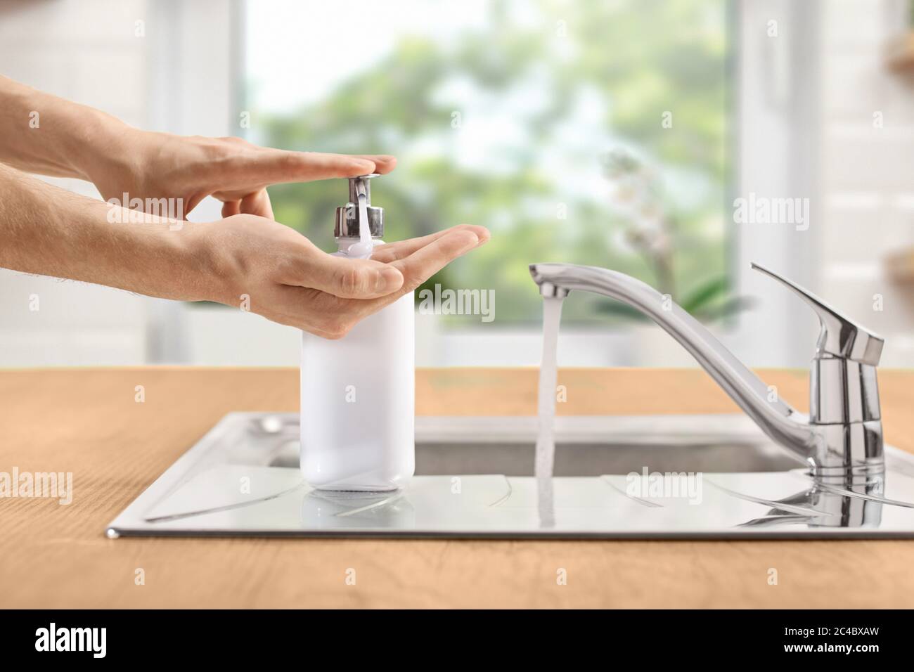 Mains de sexe masculin appuyant sur une bouteille de savon liquide à côté  d'un évier dans une cuisine Photo Stock - Alamy
