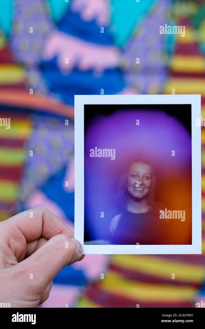 Une femme tenant un portrait d'elle-même aura Polaroid. Banque D'Images