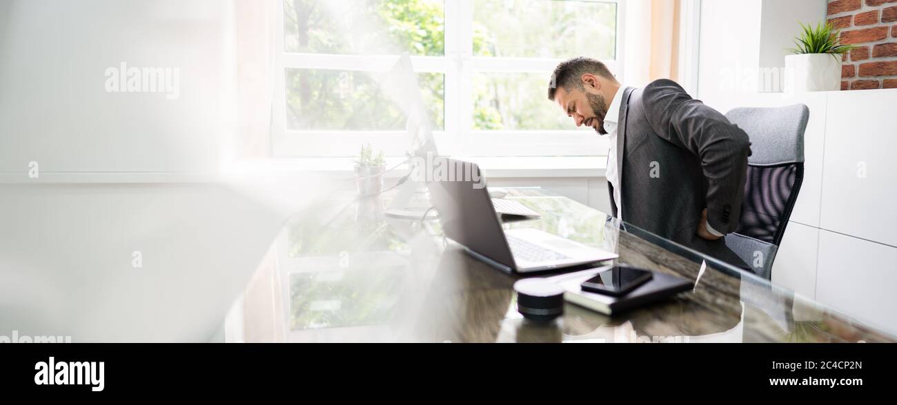 Homme souffrant de douleurs dorsales, stress à l'ordinateur au bureau Banque D'Images