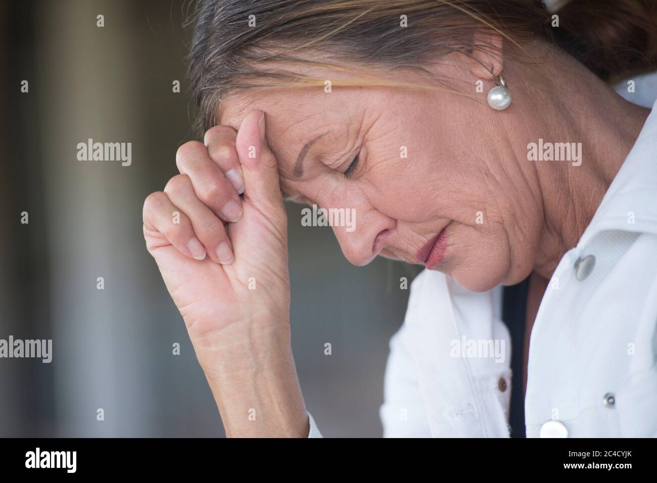 Portrait femme mûre avec triste, déprimé, expression réfléchie, seul avec les yeux fermés, dévasté et inquiet, arrière-plan flou, espace de copie. Banque D'Images