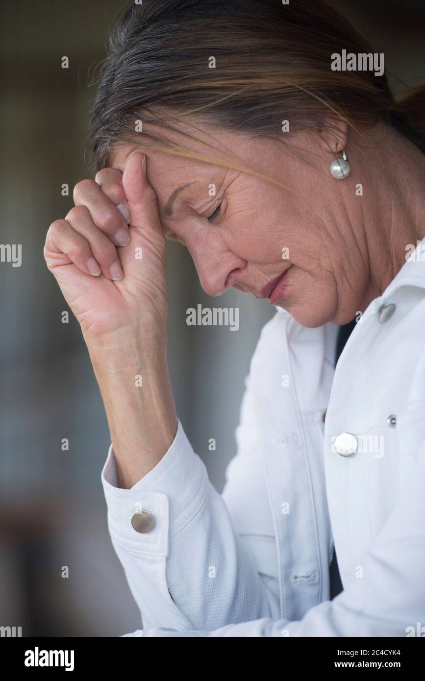 Portrait femme mature dans triste, déprimé, humeur réfléchie, seul avec les yeux fermés, dévasté et inquiet, arrière-plan flou. Banque D'Images