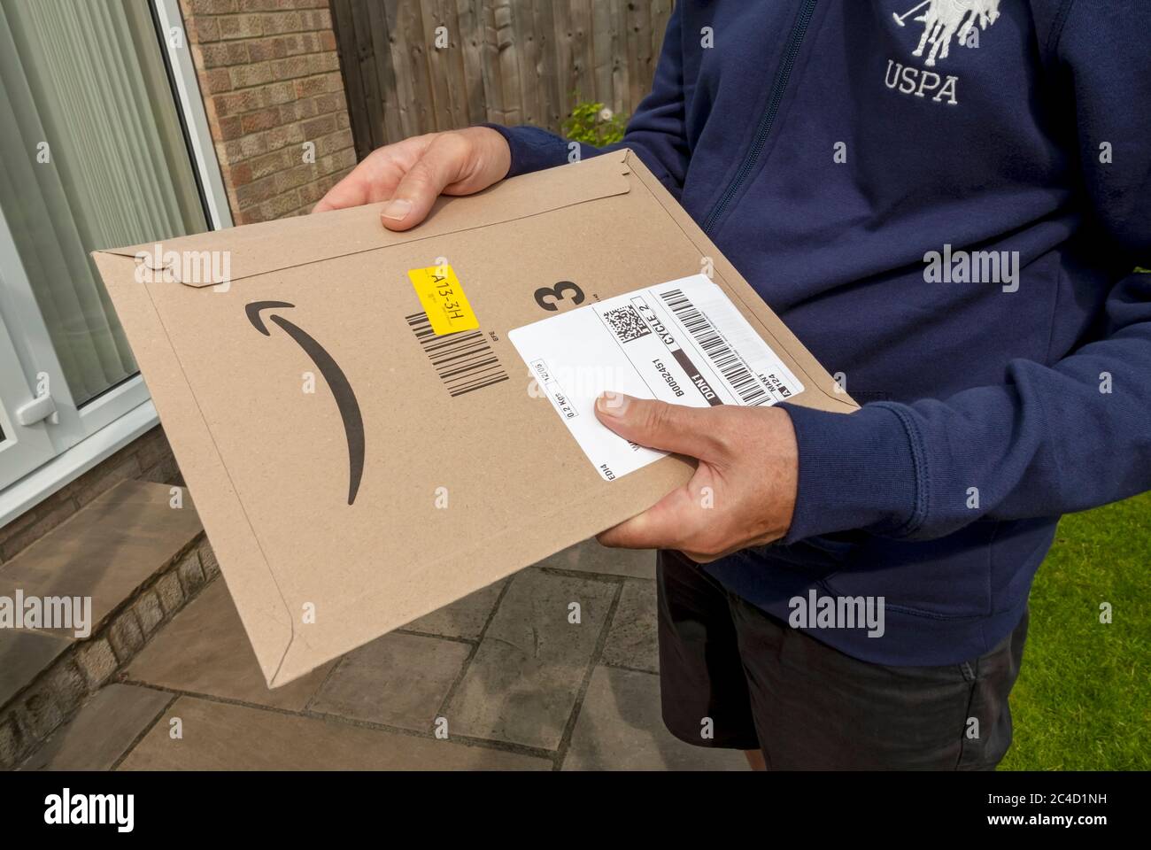 Gros plan de l'homme personne tenant Amazon paquet de livraison paquet colis home Internet shopping Angleterre Royaume-Uni Grande-Bretagne Banque D'Images