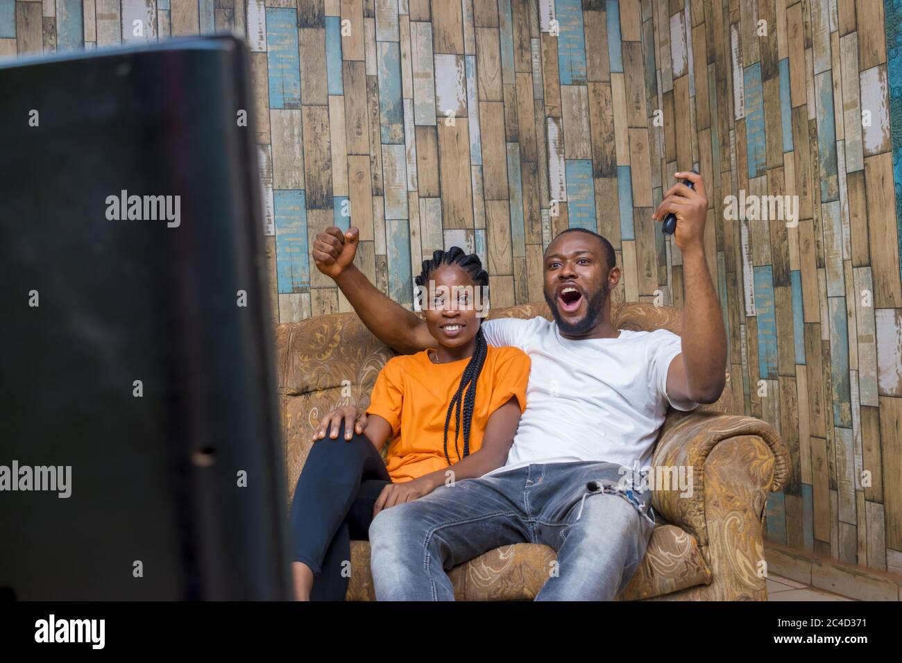 Couple afro-américain regardant un match à la télévision avec beaucoup d'enthousiasme Banque D'Images