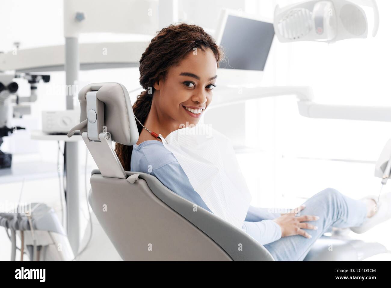 Femme noire gaie assise dans une chaise de dentiste Banque D'Images