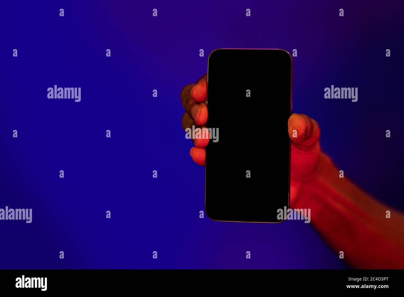 Main d'homme tenant le téléphone mobile montrant un écran vide, fond bleu Banque D'Images