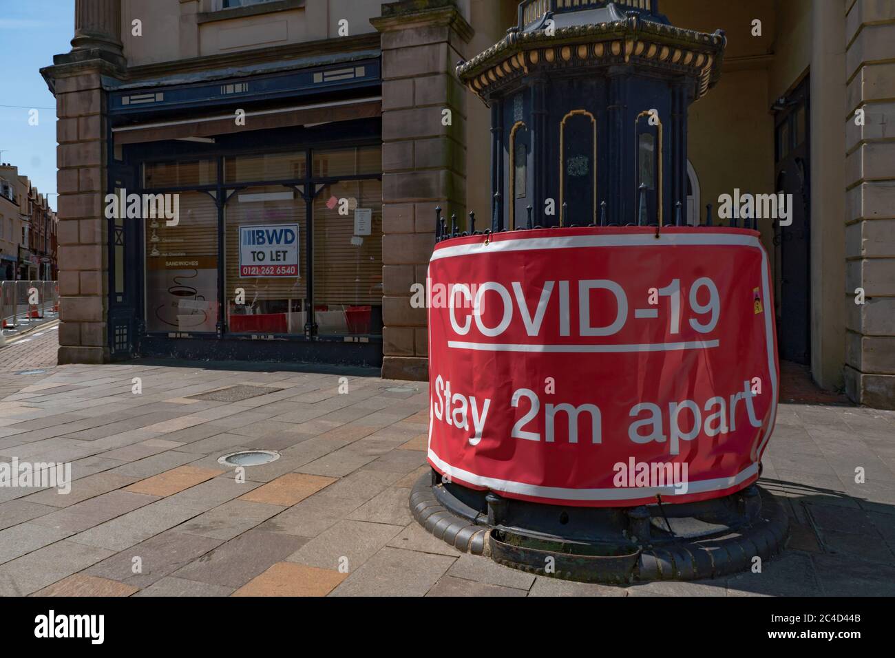 Grand panneau d'avertissement rouge Covid-19 à 2 m de distance, avec des affaires fermées derrière. Stourbridge. West Midlands. ROYAUME-UNI Banque D'Images