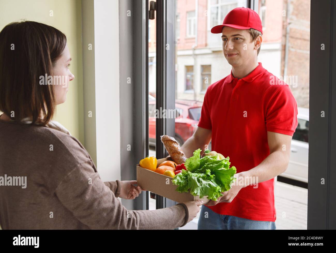 Gagnez du temps et livrez vos commandes en ligne à l'épicerie. Le coursier donne la commande à la fille Banque D'Images