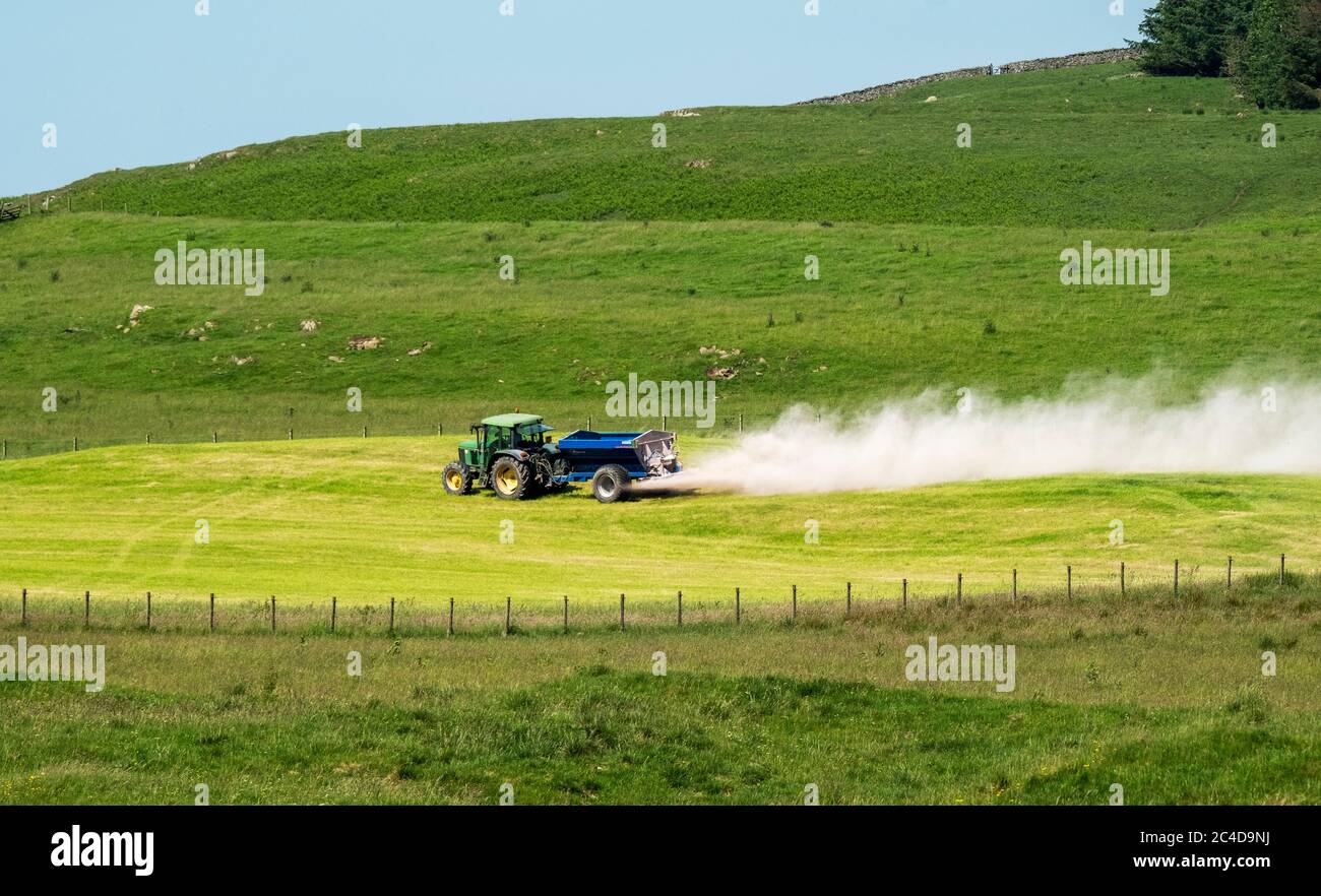 Tracteur et remorque qui épandent de la chaux sur un terrain de gazon près de Shankend, Hawick, aux frontières écossaises. Banque D'Images