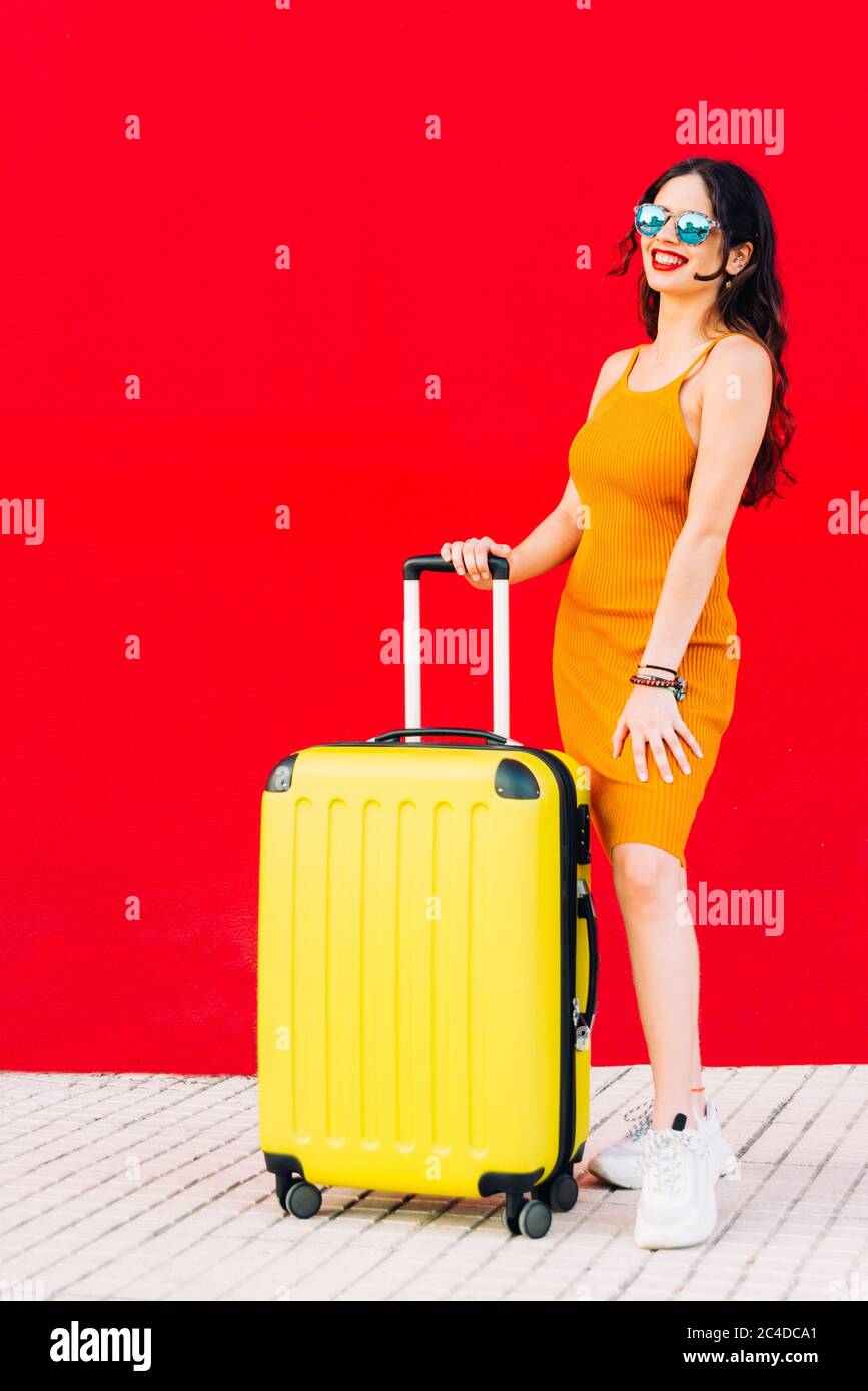 une femme heureuse tenant sa valise et souriant debout Banque D'Images