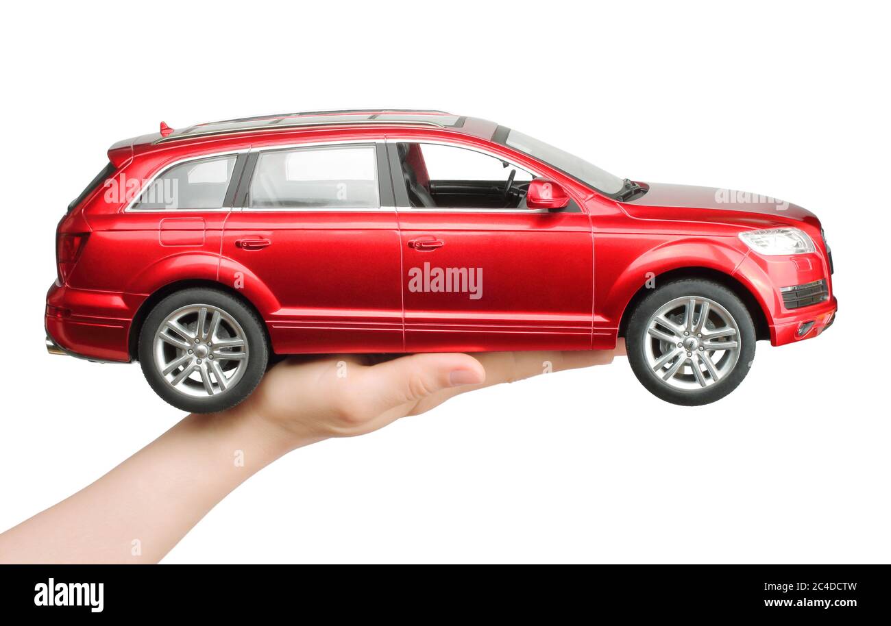 Kiev, Ukraine - 15 mai 2019: Main de femme tenant une grosse voiture rouge jouet Audi sur fond blanc Banque D'Images