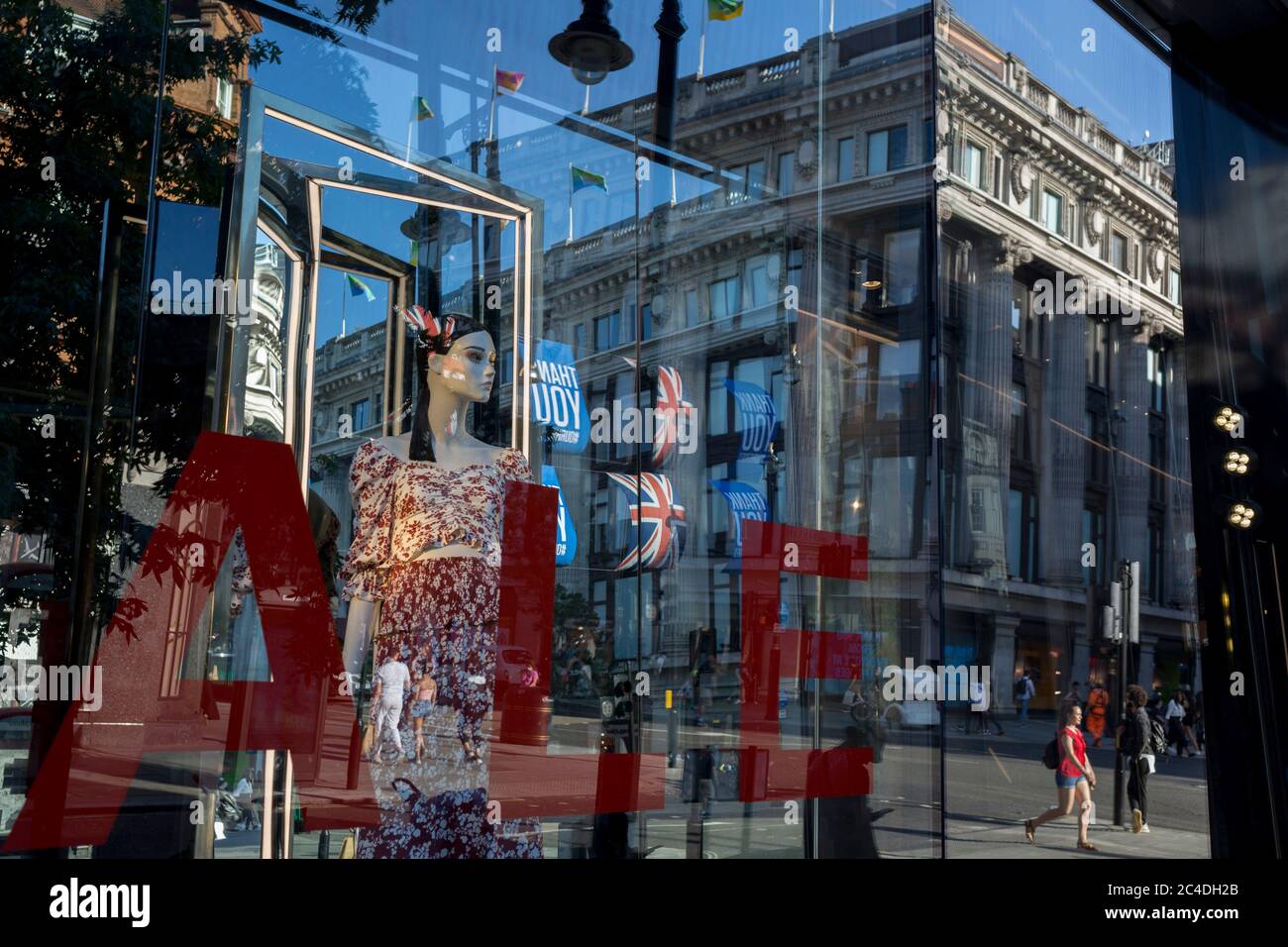 149 autres personnes ont déclaré mourir du coronavirus au cours des 24 dernières heures, ce qui a porté le nombre de morts au Royaume-Uni à 43,320, et les acheteurs sont déformés par la fenêtre de vente du magasin « Zara » d'Oxford Street, qui a récemment rouvert des affaires de ennemis après avoir assoupi les règles de confinement. Les drapeaux de Union Jack pendent à côté des bannières de remerciement pour soutenir les principaux travailleurs du NHS (National Health Service) pendant la pandémie de Covid, le 25 juin 2020, à Londres, en Angleterre. Banque D'Images
