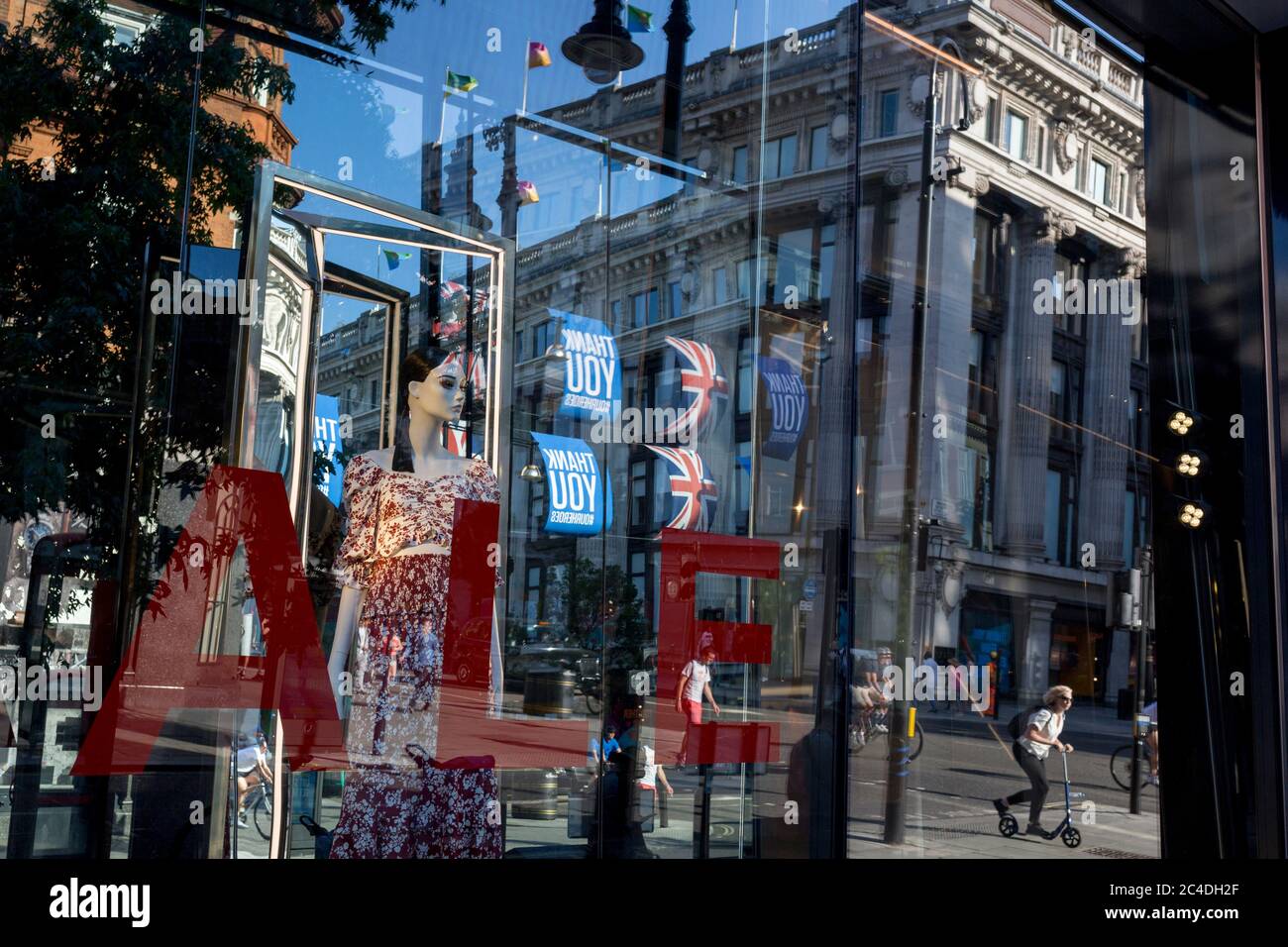 149 autres personnes ont déclaré mourir du coronavirus au cours des 24 dernières heures, ce qui a porté le nombre de morts au Royaume-Uni à 43,320, et les acheteurs sont déformés par la fenêtre de vente du magasin « Zara » d'Oxford Street, qui a récemment rouvert des affaires de ennemis après avoir assoupi les règles de confinement. Les drapeaux de Union Jack pendent à côté des bannières de remerciement pour soutenir les principaux travailleurs du NHS (National Health Service) pendant la pandémie de Covid, le 25 juin 2020, à Londres, en Angleterre. Banque D'Images