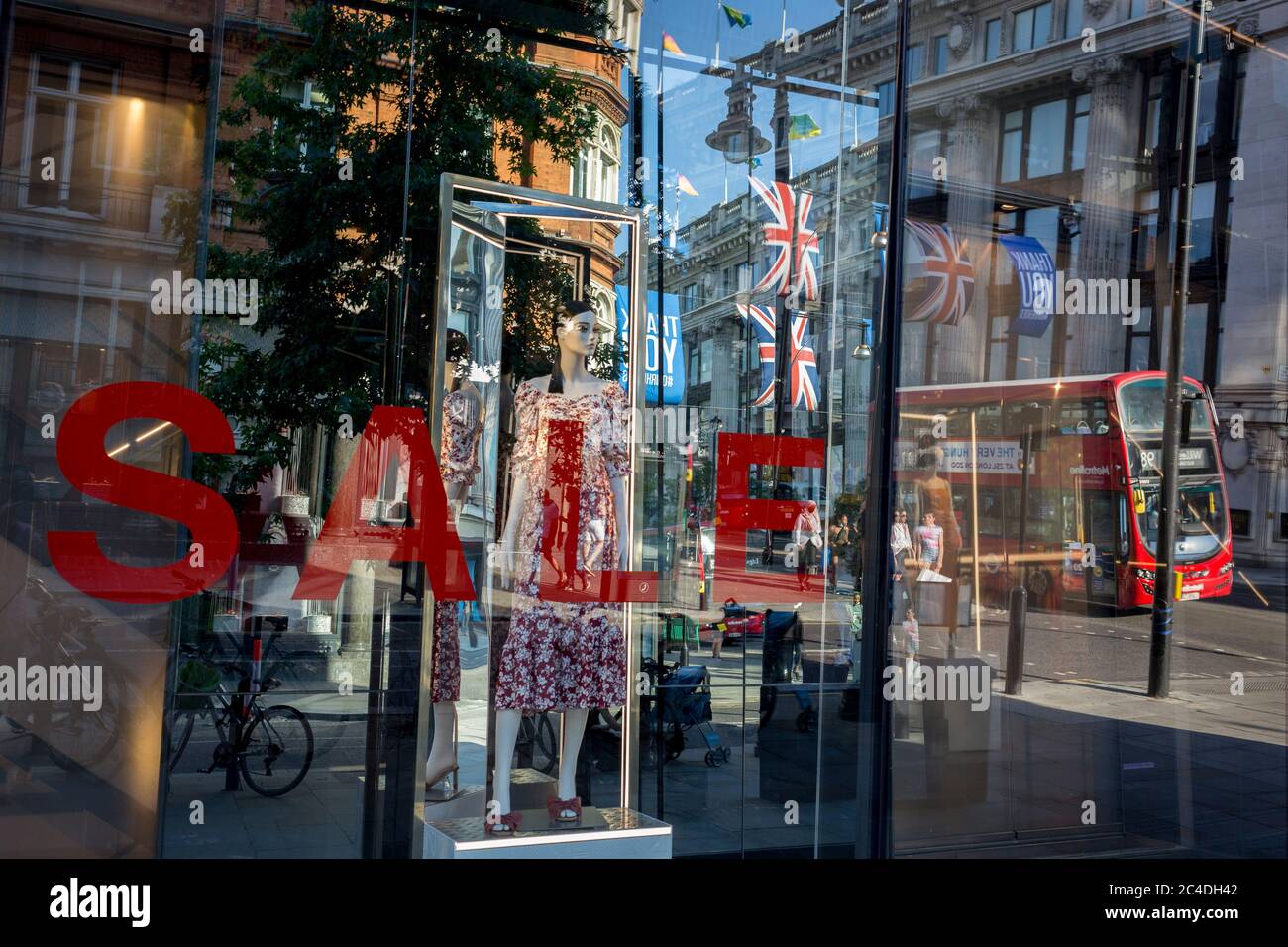 149 autres personnes ont déclaré mourir du coronavirus au cours des 24 dernières heures, ce qui a porté le nombre de morts au Royaume-Uni à 43,320, et les acheteurs sont déformés par la fenêtre de vente du magasin « Zara » d'Oxford Street, qui a récemment rouvert des affaires de ennemis après avoir assoupi les règles de confinement. Les drapeaux de Union Jack pendent à côté des bannières de remerciement pour soutenir les principaux travailleurs du NHS (National Health Service) pendant la pandémie de Covid, le 25 juin 2020, à Londres, en Angleterre. Banque D'Images