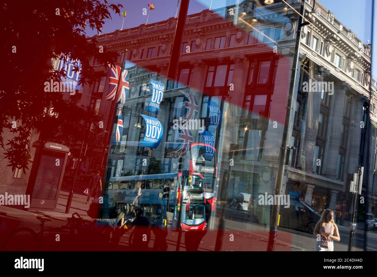 149 autres personnes ont déclaré mourir du coronavirus au cours des 24 dernières heures, ce qui a porté le nombre de morts au Royaume-Uni à 43,320, et les acheteurs sont déformés par la fenêtre de vente du magasin « Zara » d'Oxford Street, qui a récemment rouvert des affaires de ennemis après avoir assoupi les règles de confinement. Les drapeaux de Union Jack pendent à côté des bannières de remerciement pour soutenir les principaux travailleurs du NHS (National Health Service) pendant la pandémie de Covid, le 25 juin 2020, à Londres, en Angleterre. Banque D'Images