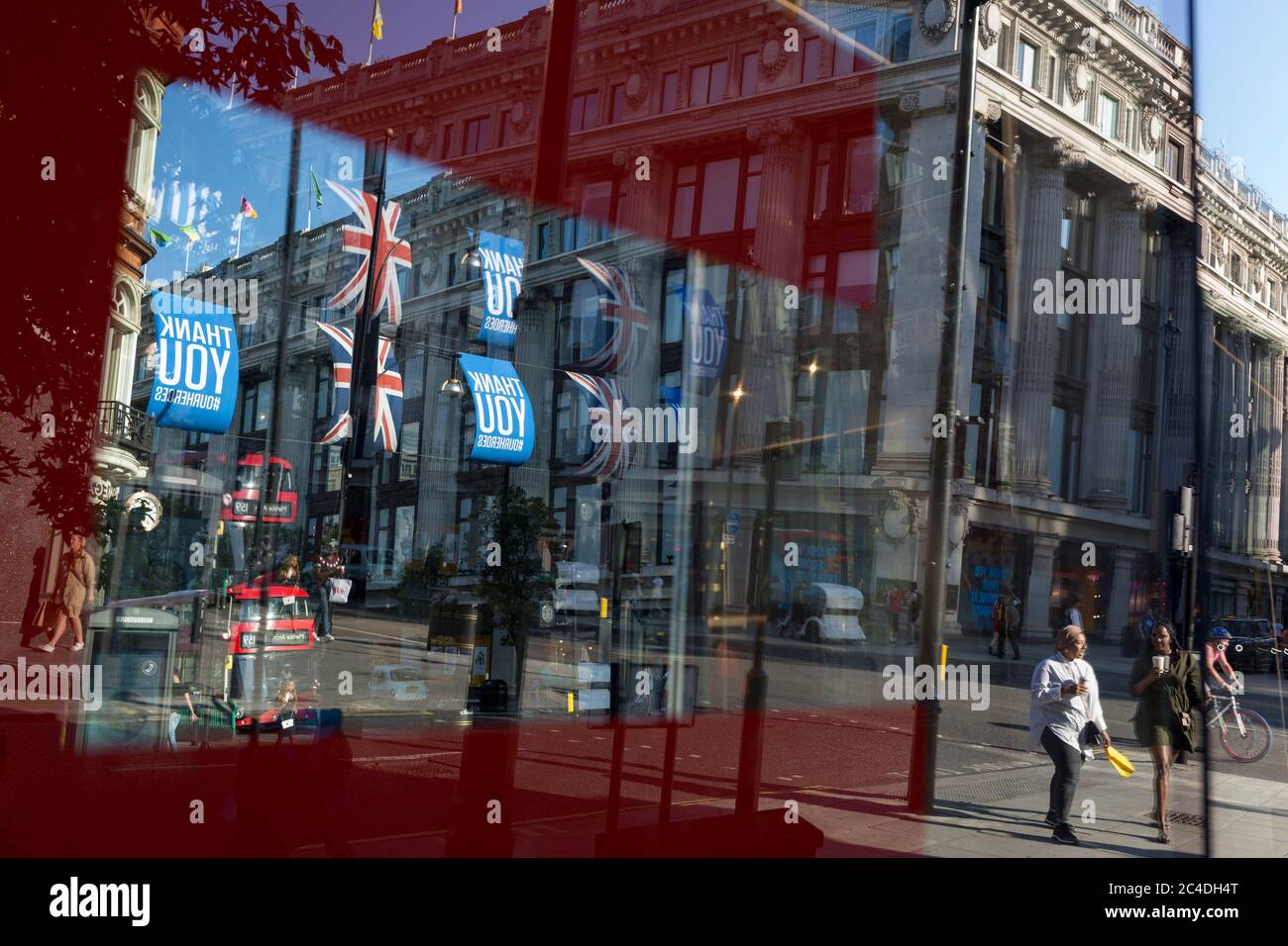 149 autres personnes ont déclaré mourir du coronavirus au cours des 24 dernières heures, ce qui a porté le nombre de morts au Royaume-Uni à 43,320, et les acheteurs sont déformés par la fenêtre de vente du magasin « Zara » d'Oxford Street, qui a récemment rouvert des affaires de ennemis après avoir assoupi les règles de confinement. Les drapeaux de Union Jack pendent à côté des bannières de remerciement pour soutenir les principaux travailleurs du NHS (National Health Service) pendant la pandémie de Covid, le 25 juin 2020, à Londres, en Angleterre. Banque D'Images