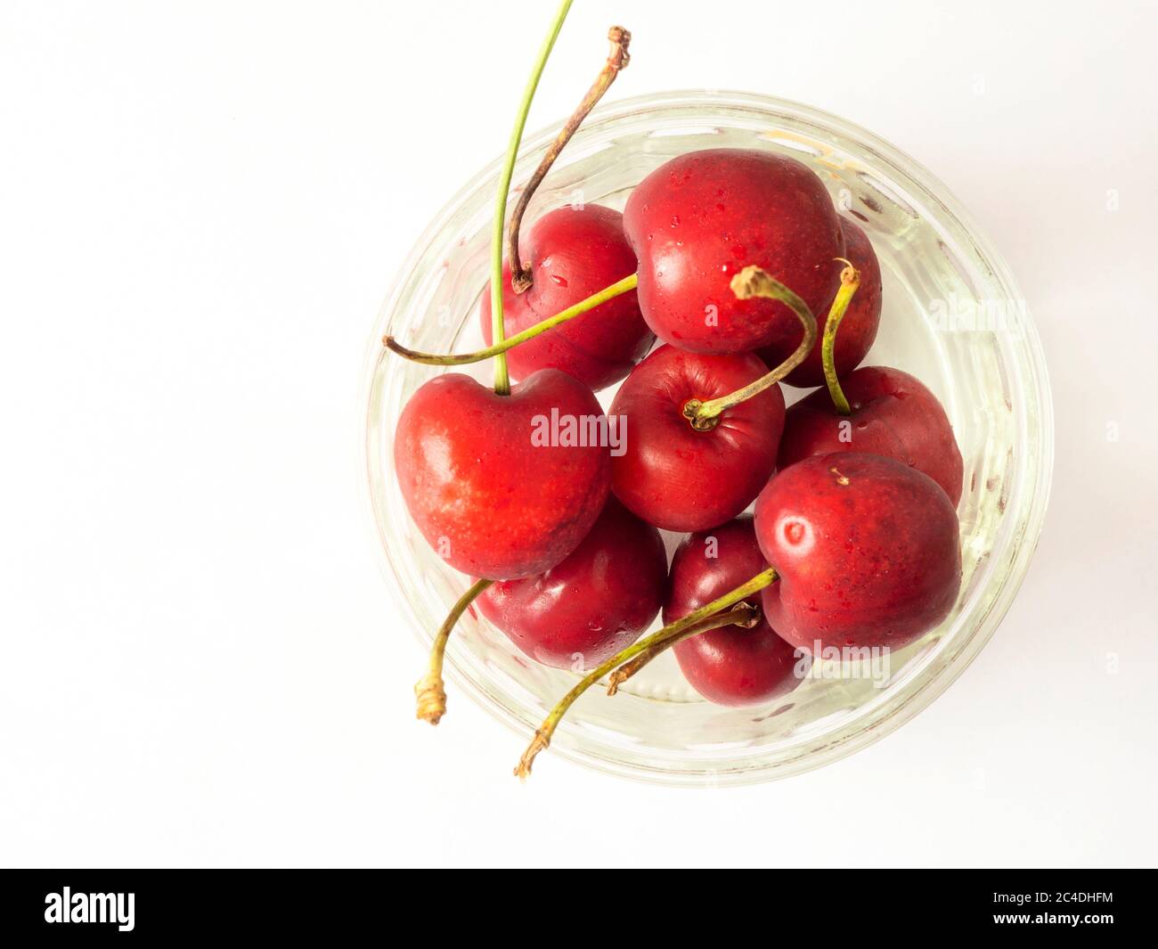 Cerises mûres fraîches dans un plat de ramequin en verre isolé sur un fond blanc avec espace de copie Banque D'Images