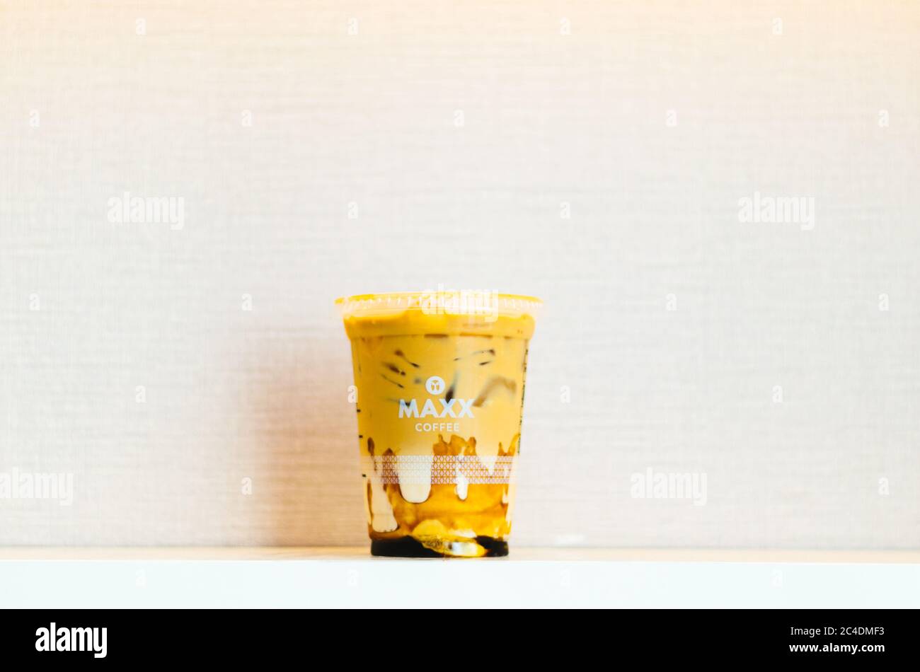 Un éditorial illustratif du café glacé Maxx au centre, au caramel, sur fond rose clair. Banque D'Images