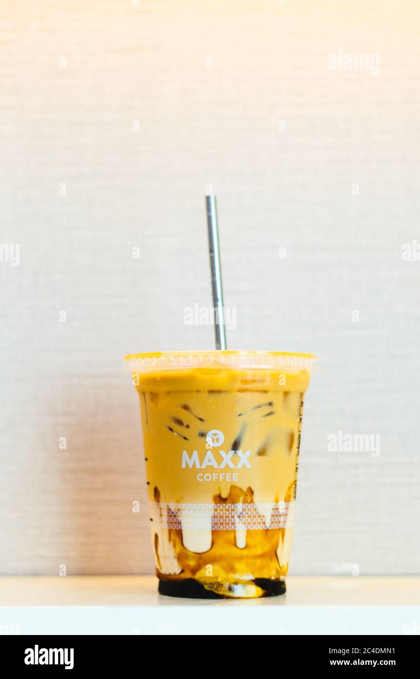 Un éditorial illustratif du café glacé Maxx au caramel et une paille en acier inoxydable au centre avec un fond rose clair. Banque D'Images