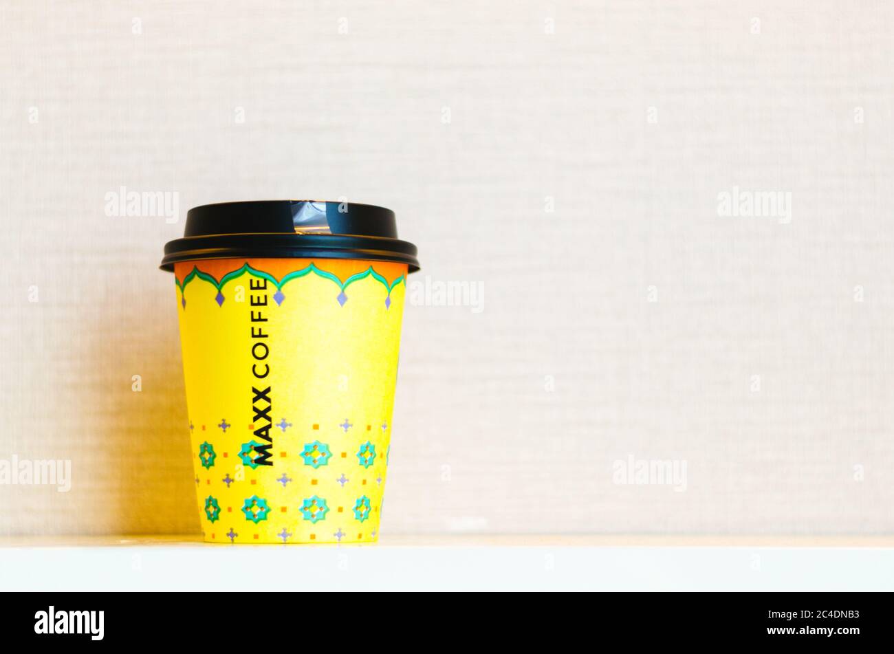 Une tasse de café à emporter jaune avec le nom de la chaîne de café Maxx inscrit au centre de la tasse. Banque D'Images