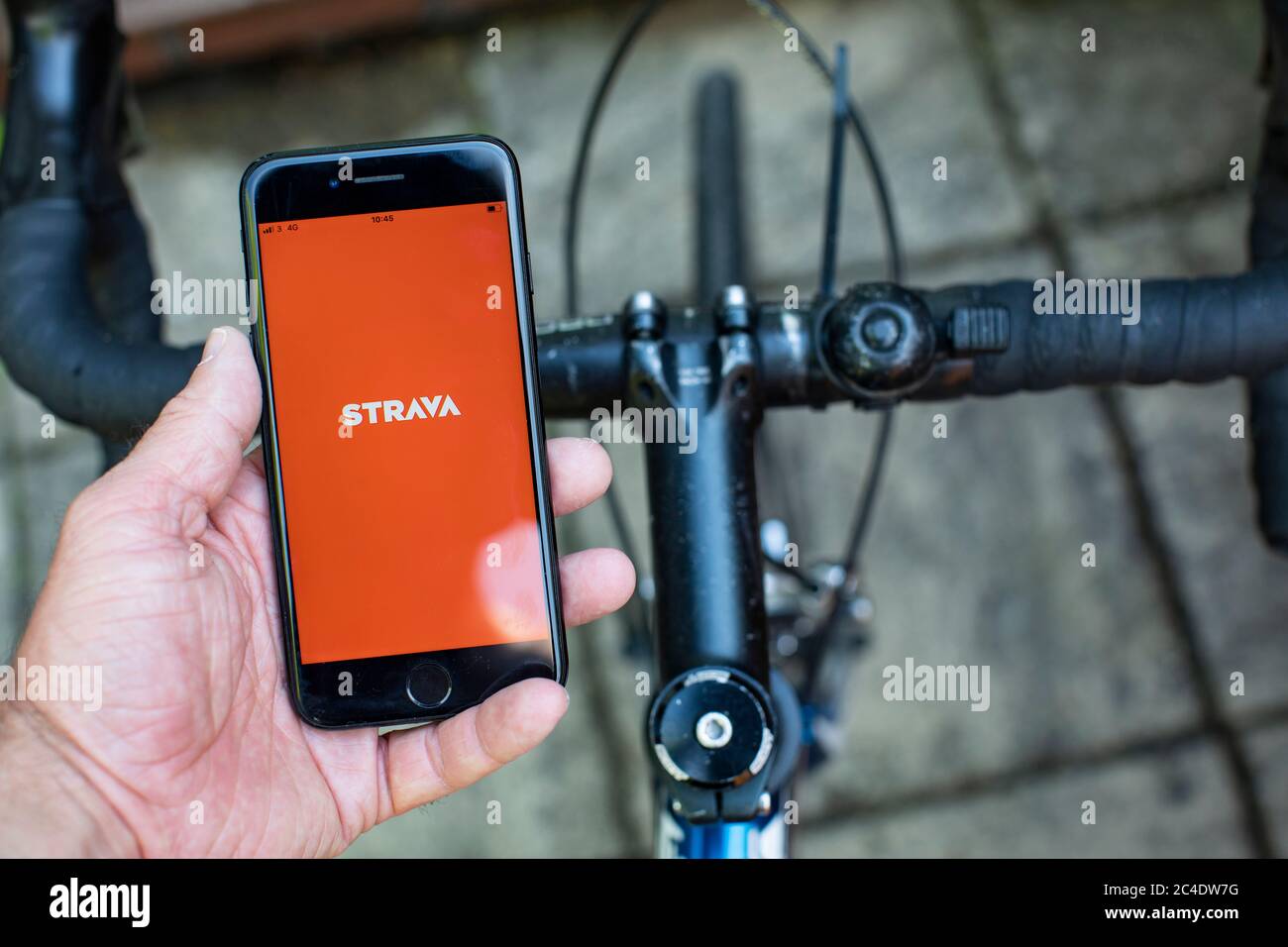 Main tenant un i-phone montrant l'application de vélo et de course Strava avec vélo. Photo de Sam Mellish Banque D'Images