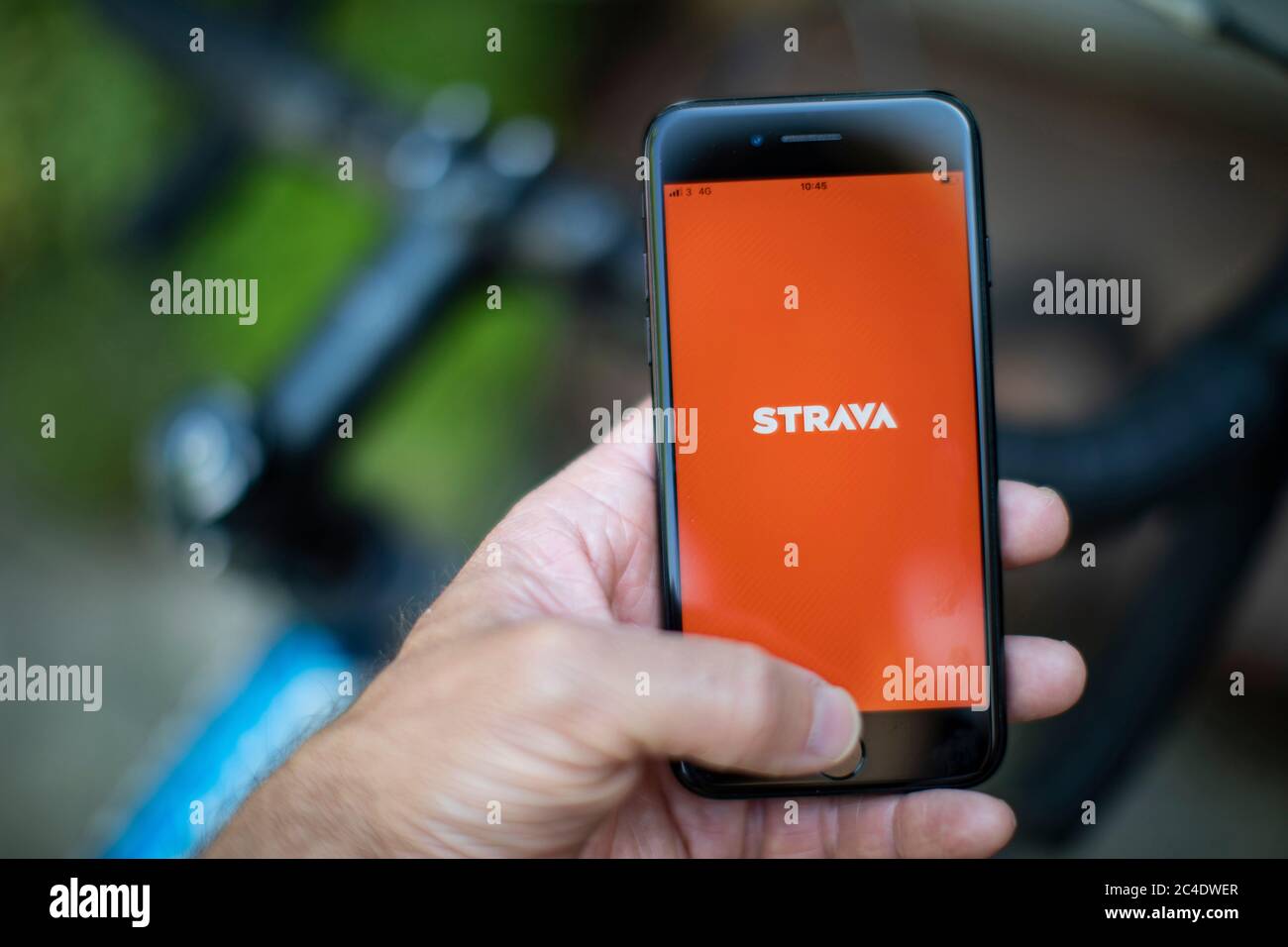 Main tenant un i-phone montrant l'application de vélo et de course Strava avec vélo. Photo de Sam Mellish Banque D'Images