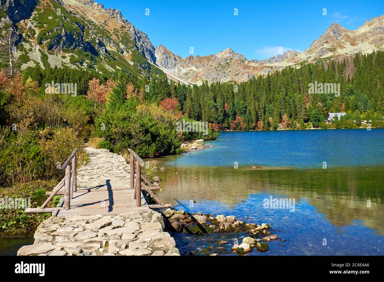 Pont en bois et passerelle en pierre au lac de Poprad d'automne avec des sommets et des forêts colorées près du parc national de High Tatras, Slovaquie Banque D'Images