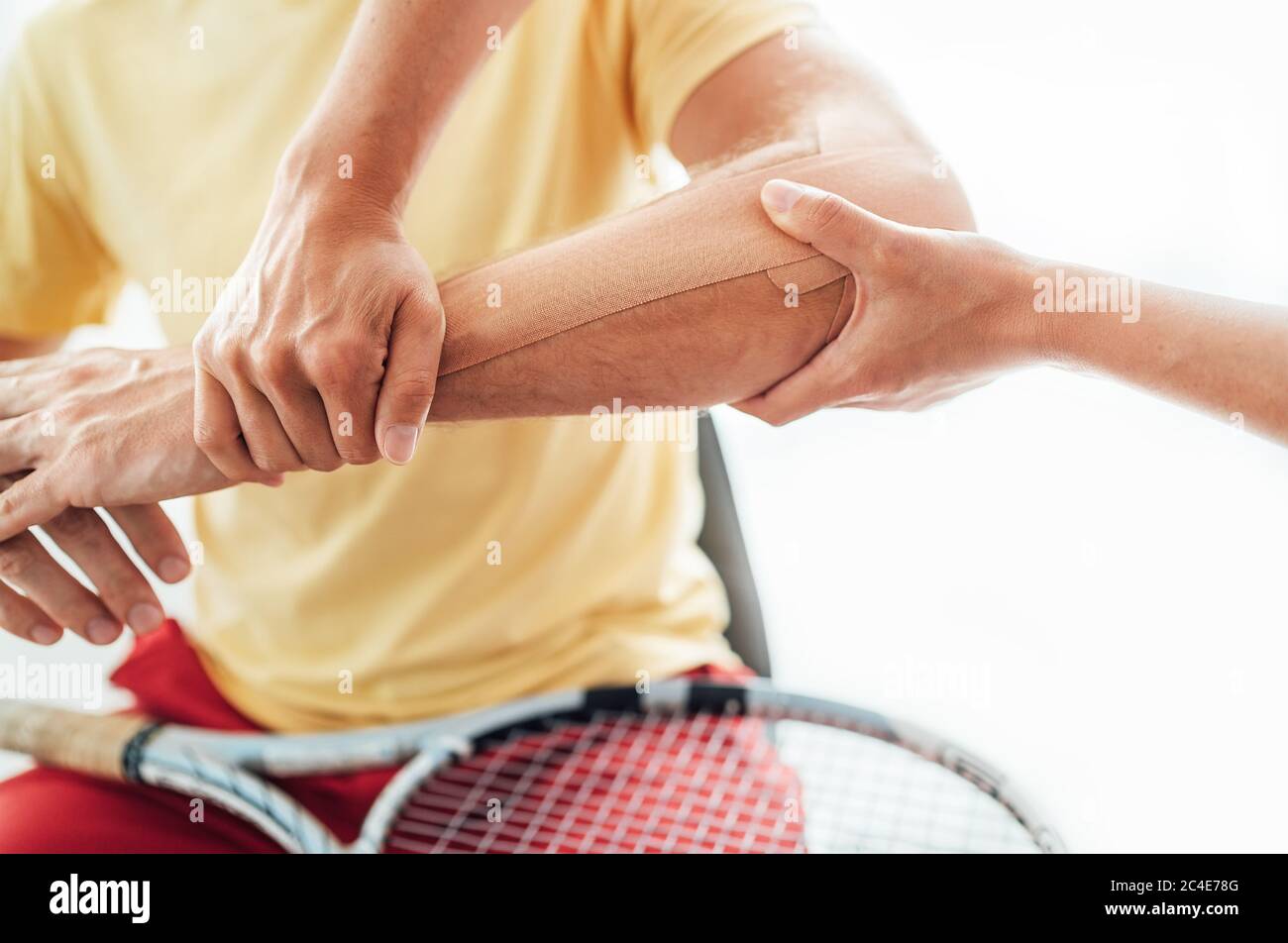Coude de joueur de tennis avec bande élastique thérapeutique ou Kinesio appliquée par l'infirmière à l'image rapprochée du service orthopédique. Active sportive personnes santé reh Banque D'Images