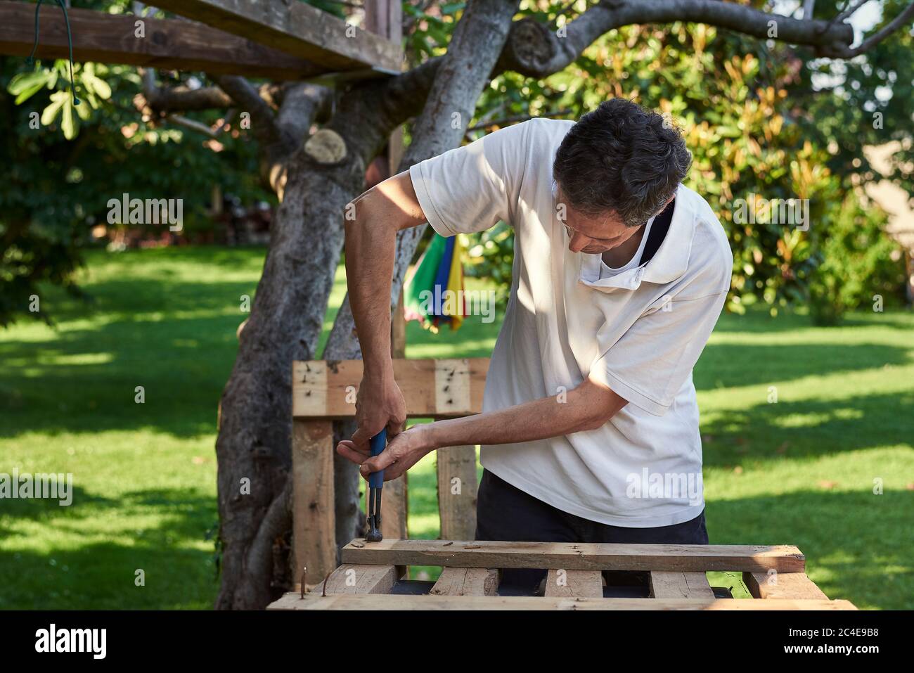 Homme senior actif en retraite travaillant dans l'arrière-cour, souriant Banque D'Images