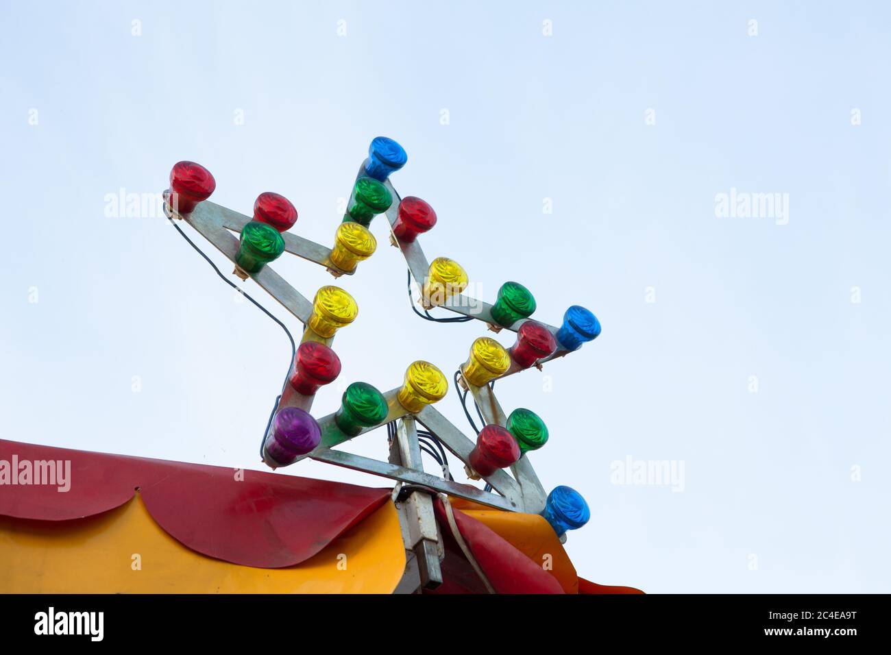 Lampe en forme d'étoile avec ampoules multicolores au sommet du cirque ou du carrousel. Illumination sur fond de ciel. Concept de divertissement Banque D'Images