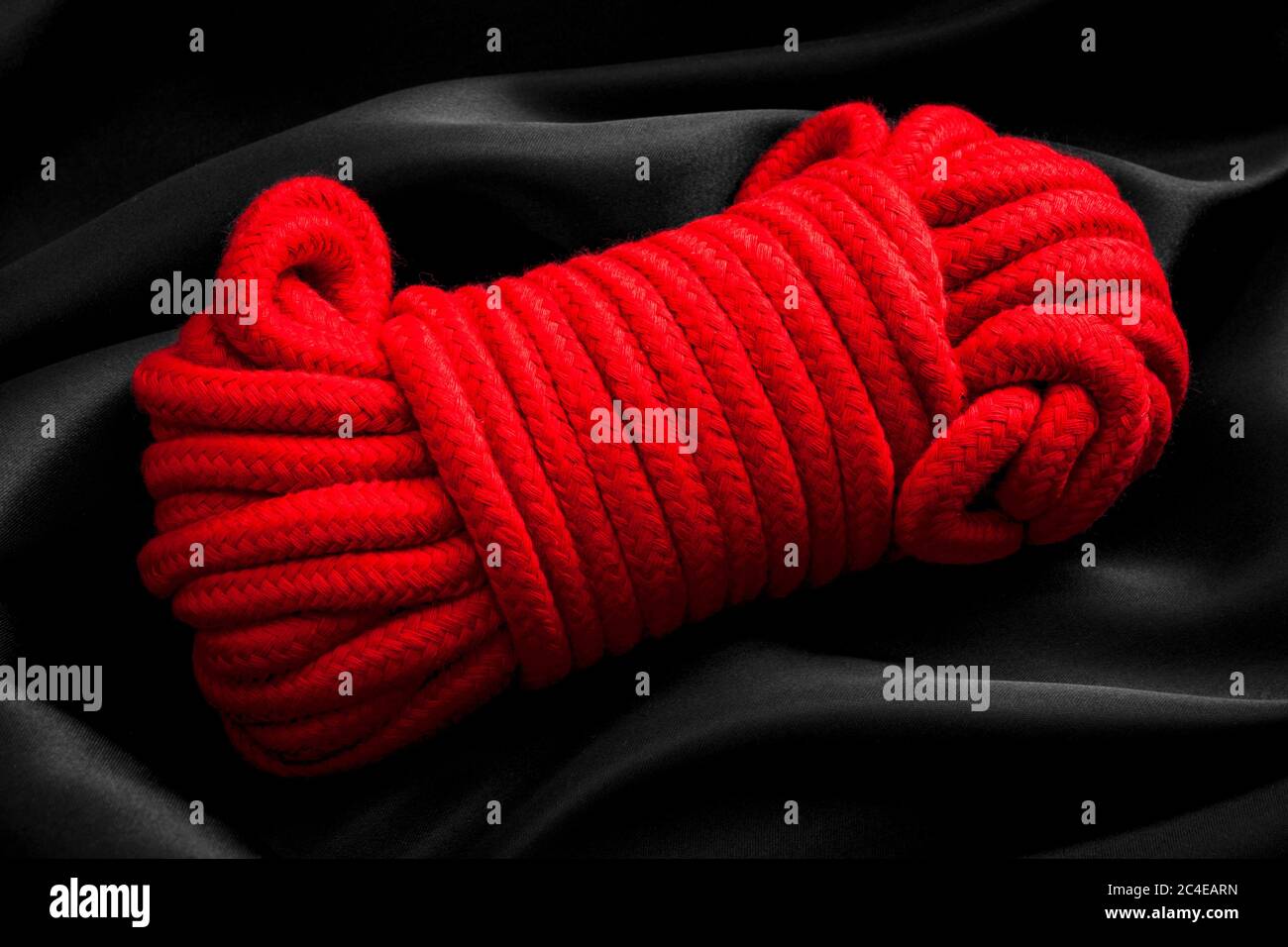 Hédonisme, jeux de corde pour adultes et concept de style de vie BDSM avec gros plan sur une boule de corde rouge, utilisé dans les arts érotiques japonais de kinbaku, sinju et Banque D'Images