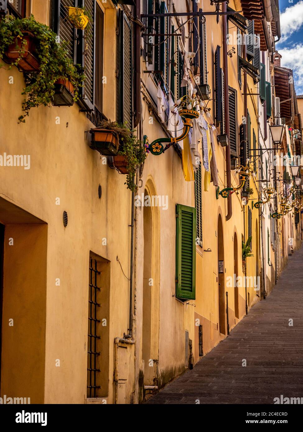 Une étroite rue escarpée longeant une rangée de maisons avec des volets en bois, Sienne. Italie. Banque D'Images