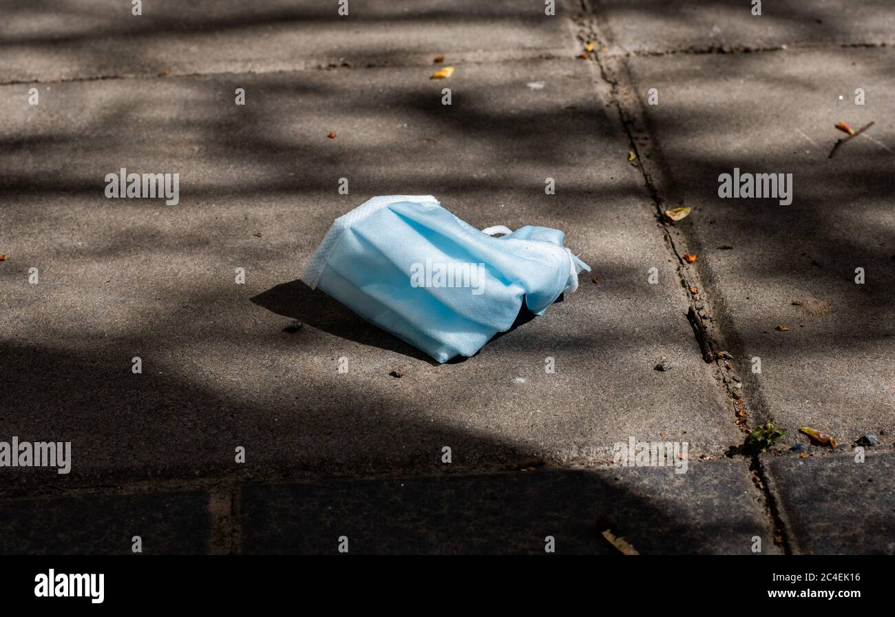 Arrêtez Covid 19. La fin du coronavirus. Les gens se défausser du masque facial de protection chirurgical dans les rues publiques. Masque médical sale posé sur le sol Banque D'Images