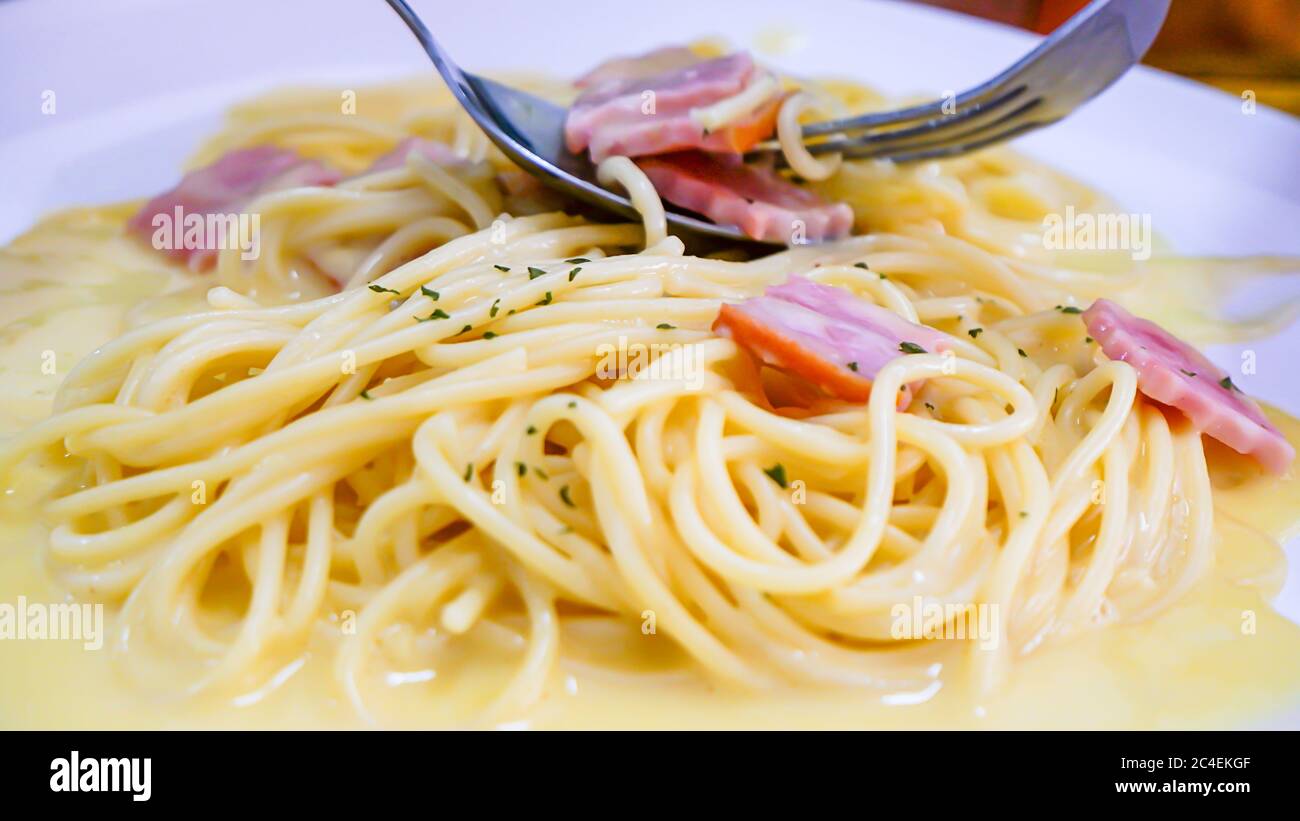Le spaghetti carbonara au fromage frit dans une assiette blanche sur la table. Banque D'Images