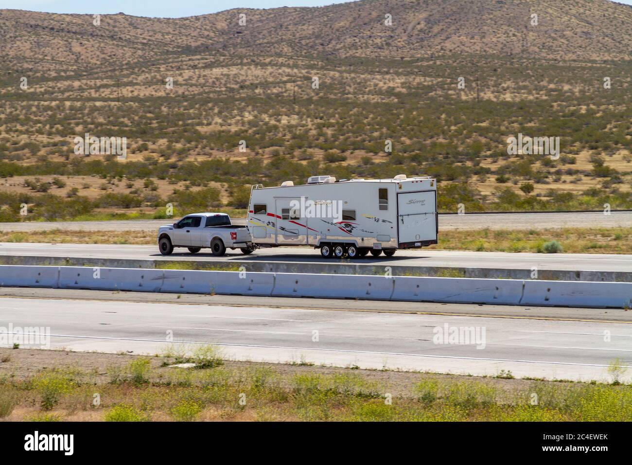 Apple Valley, CA / USA – 16 mai 2020 : un camion tractant une remorque de camping-car sur l'Interstate 15 dans le désert de Mojave près de la ville d'Apple Valley, Californie. Banque D'Images