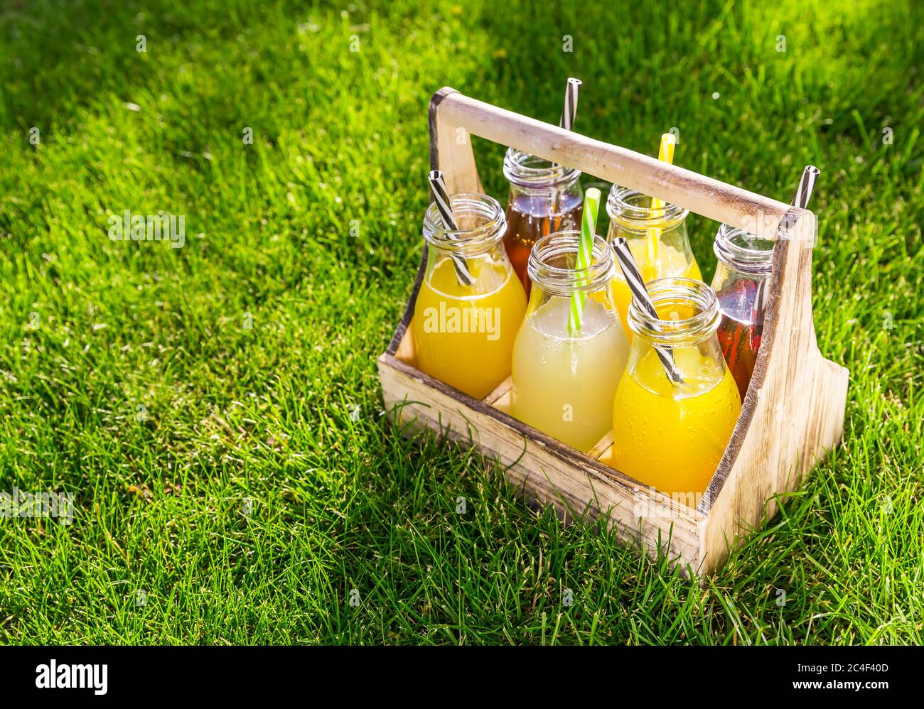 Assortiment de limonade et de thé glacé en bouteilles dans un rack en bois dans l'herbe Banque D'Images