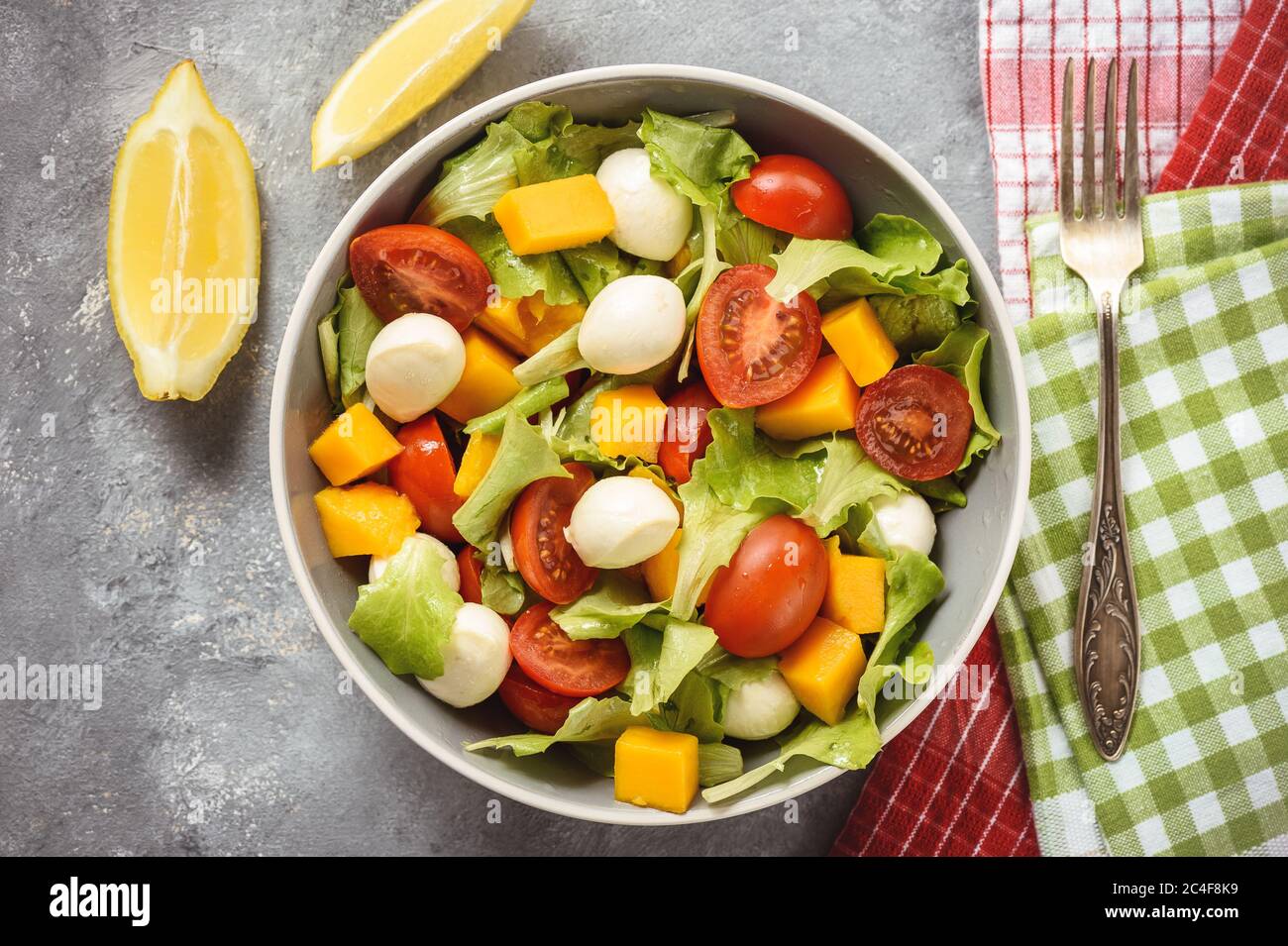 Salade avec mangue, tomates, mozzarella et citron. Banque D'Images