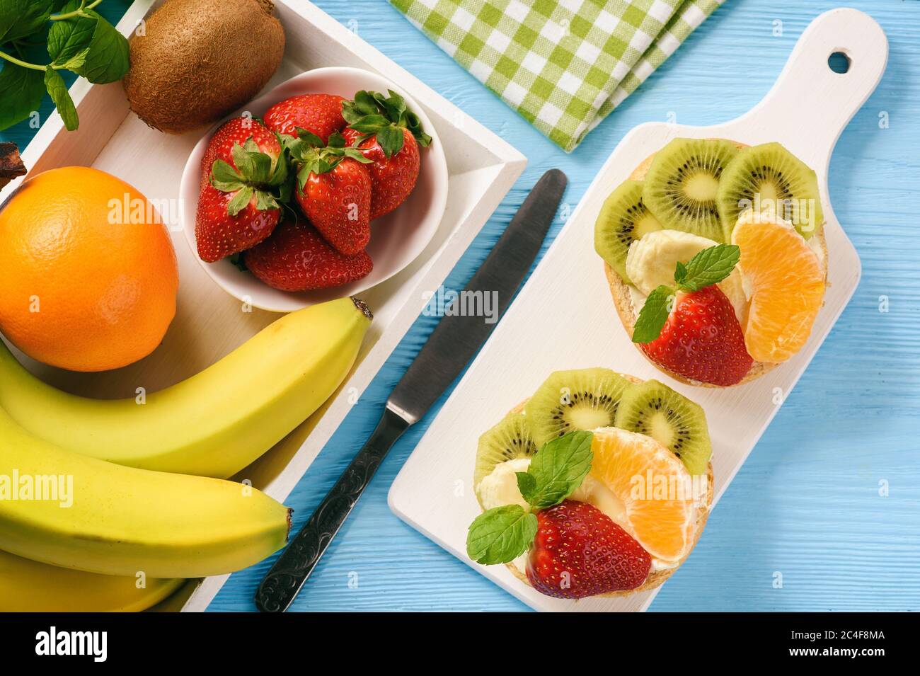 Des fruits sains pour le petit déjeuner et des sandwiches à la ricotta, accompagnés de fraises, de kiwi et d'orange. Banque D'Images