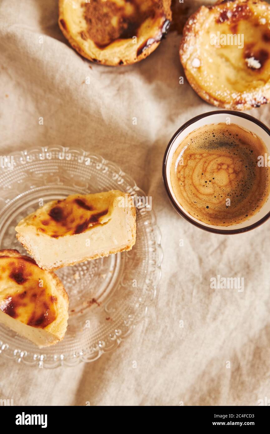 Photo verticale de délicieux tartes aux œufs portugais avec une tasse d'espresso sur une table blanche Banque D'Images