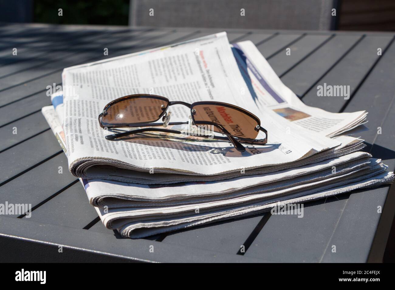 Pile de journaux et de lunettes de soleil sur une table dans un jardin  Photo Stock - Alamy