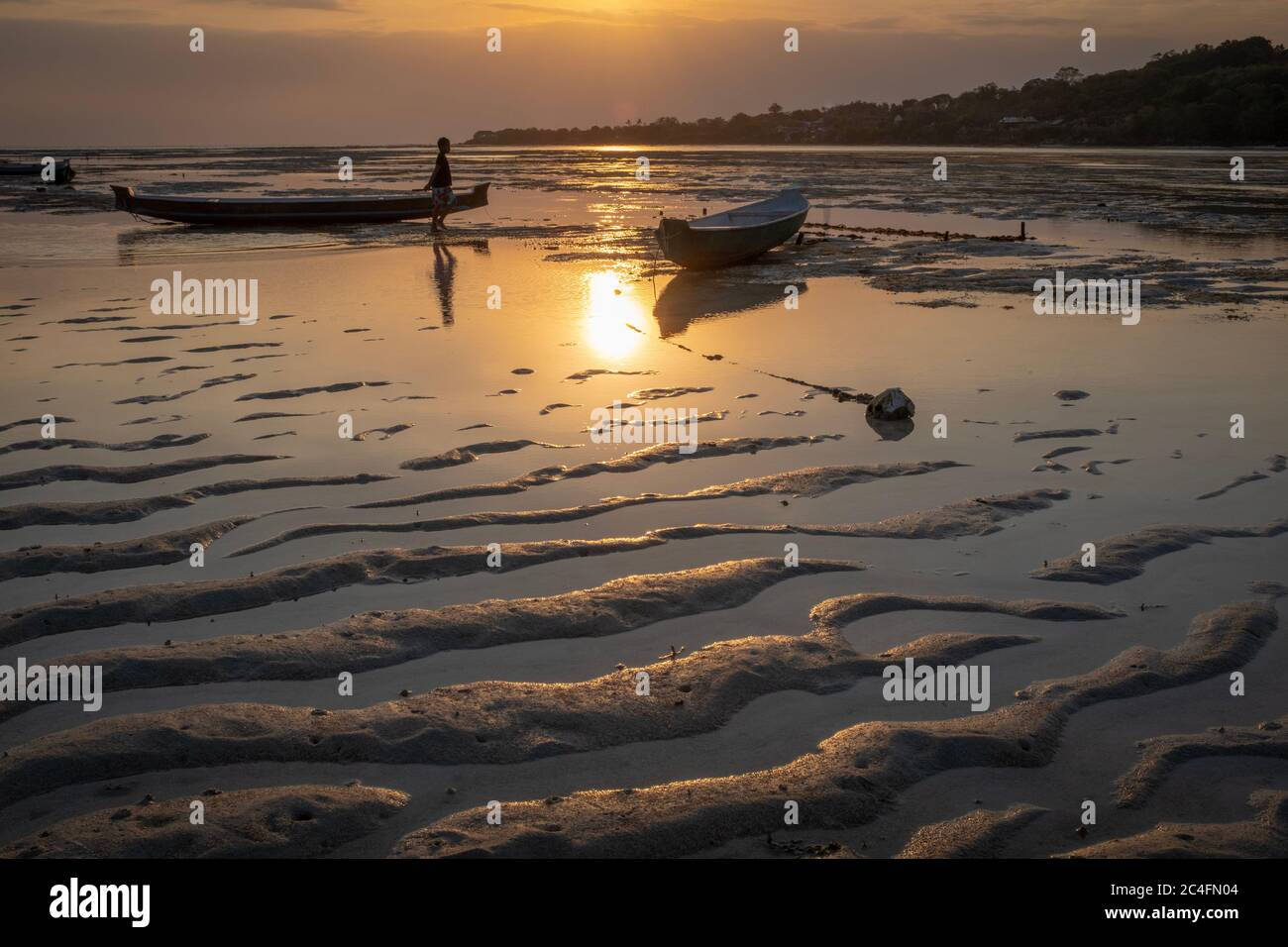 Nusa Ceningan, Bali, Indonésie - 18 mai 2018 : deux bateaux bloqués sur le sable au coucher du soleil, avec une personne méconnaissable Banque D'Images