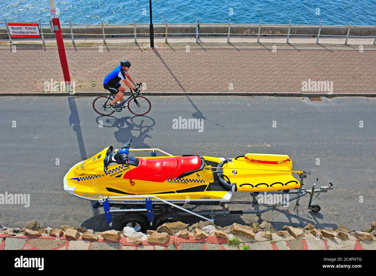 Cycliste passant la patrouille de plage sauvetage jet ski garés sur le Promenade en bord de mer à Blackpool Banque D'Images