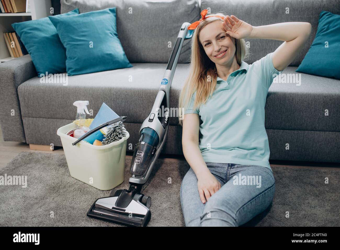 Femme fatiguée se relaxant sur le sol après avoir nettoyé son propre appartement Banque D'Images