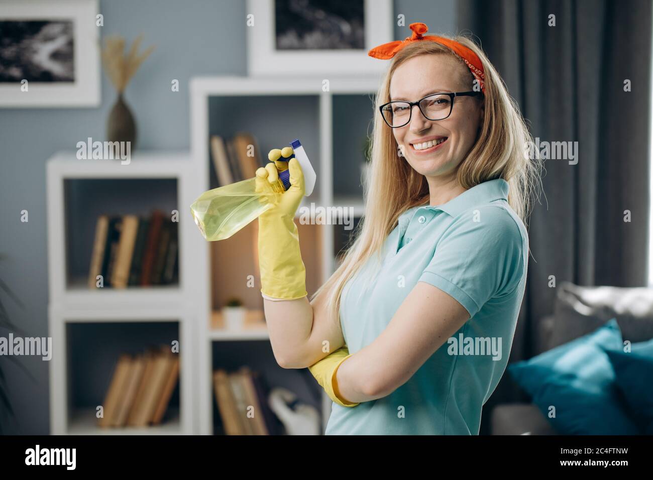 Belle femme en gants de caoutchouc tenant le spray nettoyant Banque D'Images