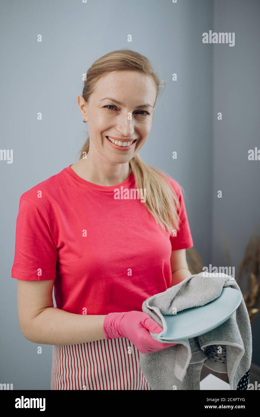 Femme charmante utilisant une serviette de cuisine pour nettoyer les plats Banque D'Images