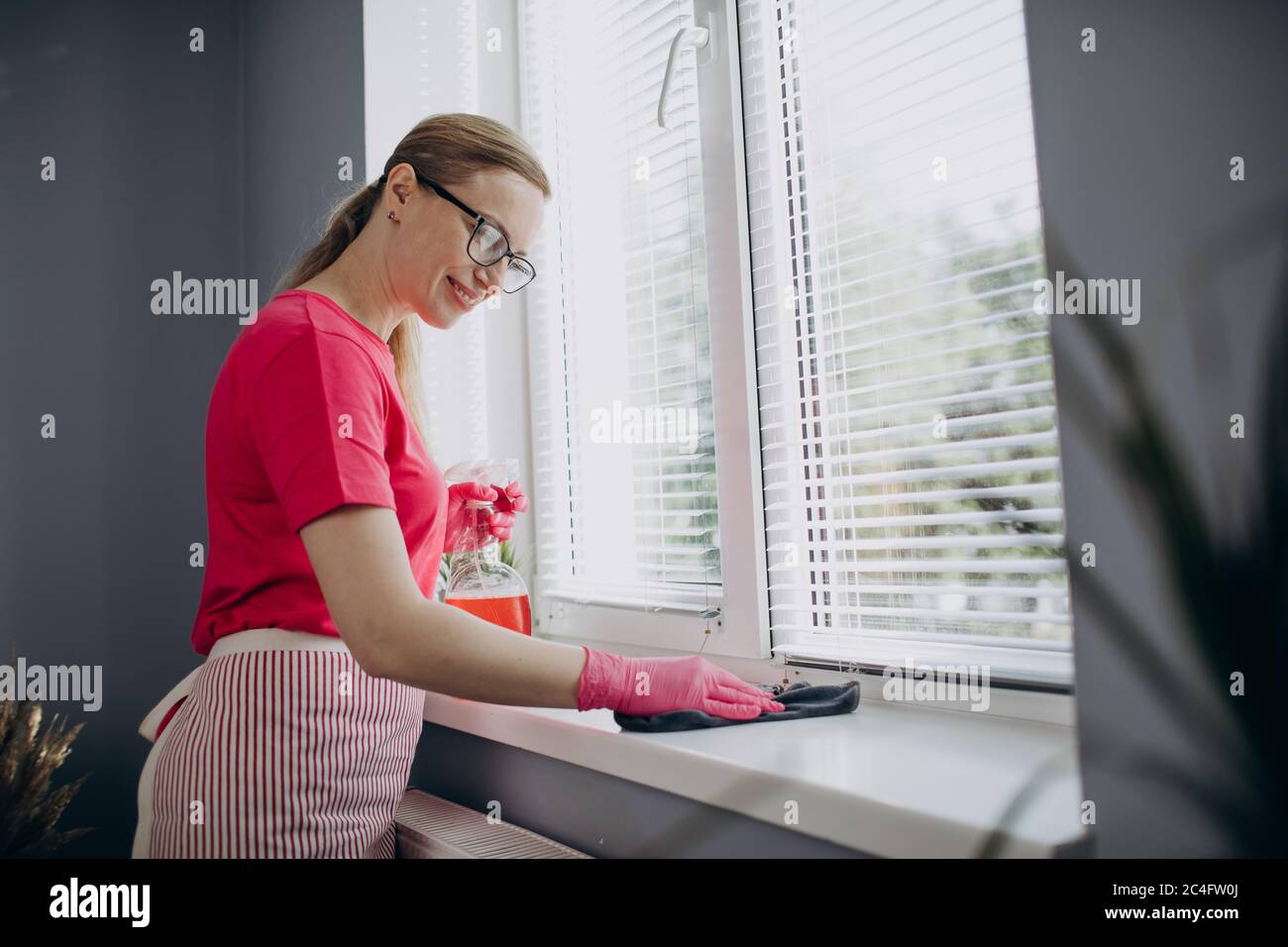 Nettoyage de la bordure de fenêtre de la femme de ménage avec un chiffon et un détergent Banque D'Images