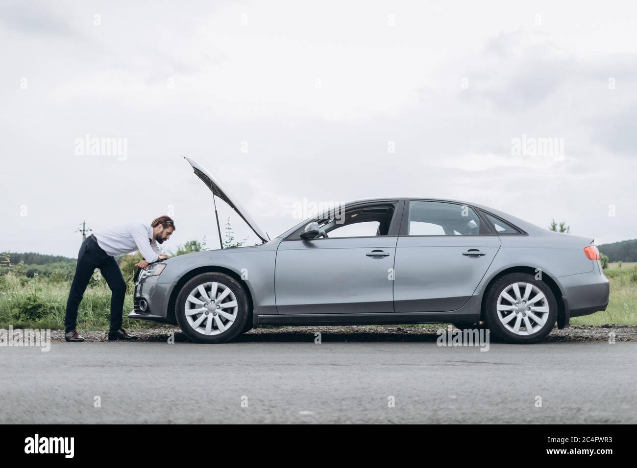 Homme regardant sous le capot de la voiture Banque de photographies et ...