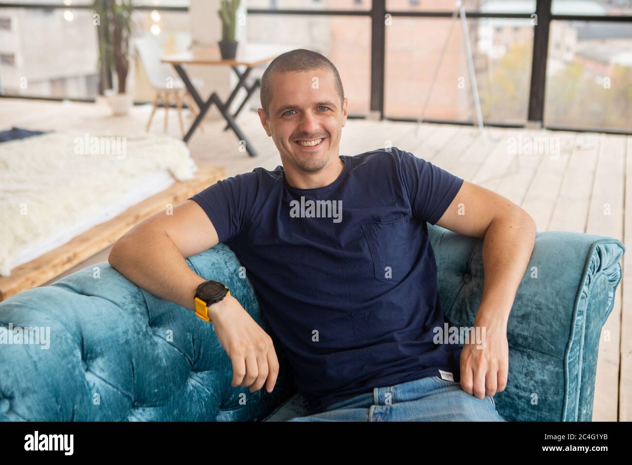 Portrait d'un homme souriant regardant dans l'appareil photo assis sur un canapé Banque D'Images