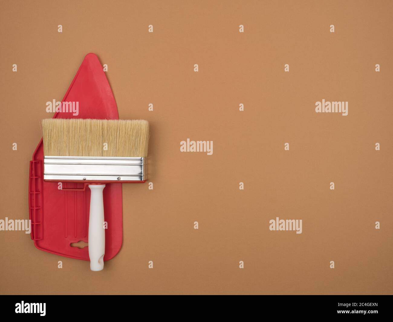 Spatule pour lisser le papier peint et un grand pinceau. Arrière-plan beige. Banque D'Images