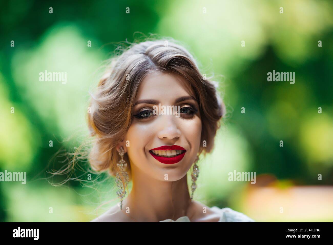 La mariée dans une robe de mariage blanche tient un bouquet sur un fond de parc vert Banque D'Images