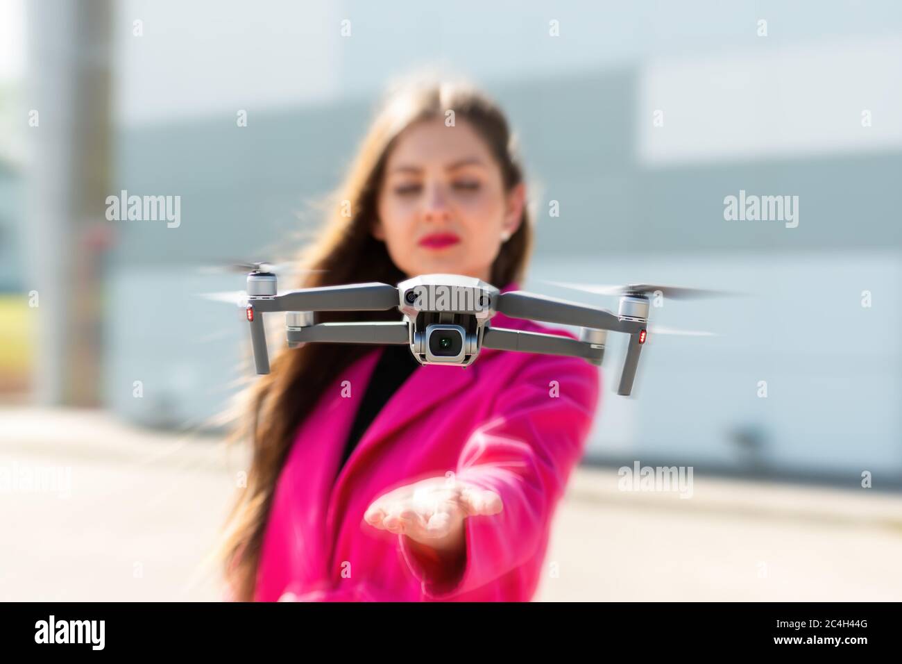 des terrains de drone sur la main, jeune femme défoqué en arrière-plan, se concentrent sur le quadricoptère Banque D'Images